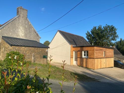 a house with a wooden garage next to a building at Les gîtes de Blandine in Peumérit