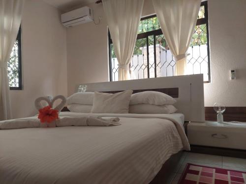 Un dormitorio con una gran cama blanca con una flor. en Reef Hills Residence FAMILY HOME, en Au Cap