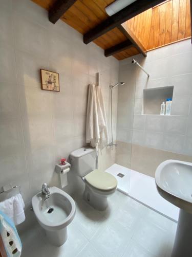 a white bathroom with a toilet and a sink at Casa Gin Tazones in Tazones