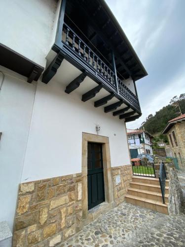 a building with a black door and a balcony at Casa Gin Tazones in Tazones