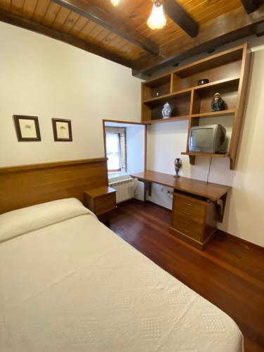 a bedroom with a bed and a desk and a tv at Casa Gin Tazones in Tazones
