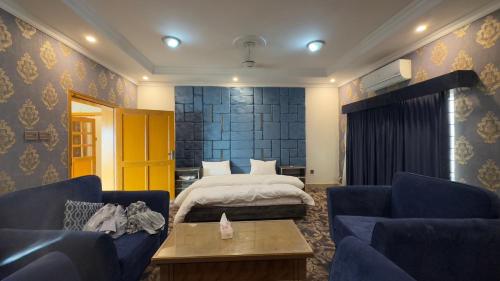 a hotel room with a bed and two blue chairs at Secure Inn Hotel in Rawalpindi