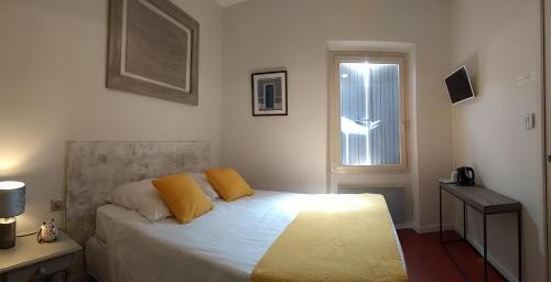 - une chambre avec un lit doté d'oreillers jaunes et d'une fenêtre dans l'établissement Mas de Camejean, à Lambesc