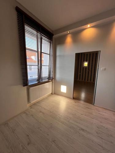 an empty room with a wooden floor and a large window at Klimatyczne mieszkanie w krainie jezior in Biskupiec