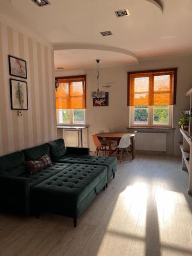 a living room with a green couch and a table at Klimatyczne mieszkanie w krainie jezior in Biskupiec