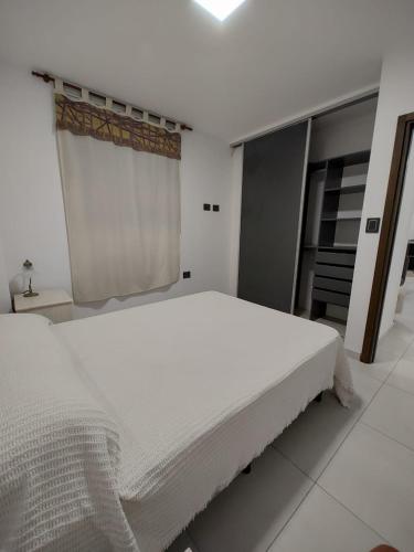 a white bedroom with a large bed and a window at Temporario catamarca in San Fernando del Valle de Catamarca