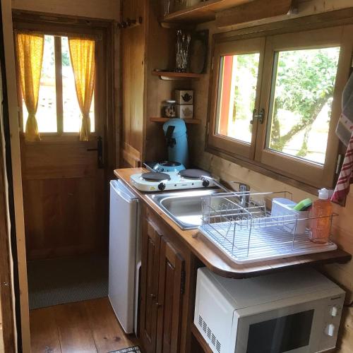 une petite cuisine avec un évier et une cuisinière dans l'établissement La roulotte de moulin rouge, à Audelange