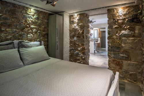 Cama en habitación con pared de piedra en Stone House, en Atenas