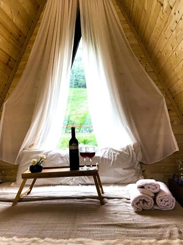 a bed with a table with two glasses of wine at Cottage Rest in kazbegi in Kazbegi