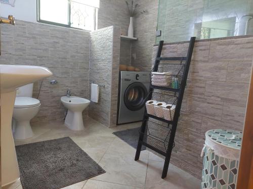 a bathroom with a washing machine and a toilet at Reef Hills Residence FAMILY HOME in Au Cap