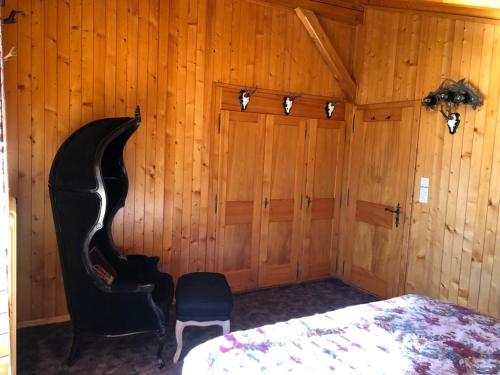 Chalet Bellevue, Villars-sur-Ollon في Ollon: غرفة نوم بجدران خشبية وسرير وكرسي