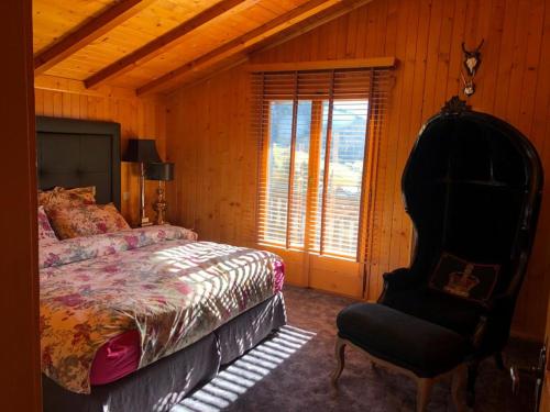 una camera con un letto e una sedia e una finestra di Chalet Bellevue, Villars-sur-Ollon a Ollon