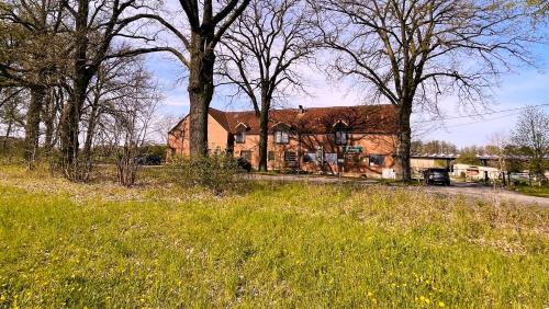 a large brick house in a field with trees at Eichenhof Hotel Garni in Groß Köris