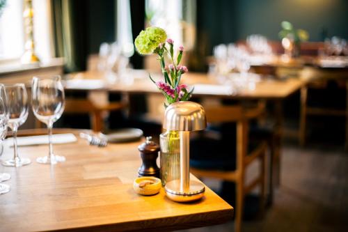a wooden table with a vase with flowers on it at Hostrups Hotel in Tønder