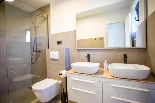 a bathroom with two sinks and a toilet and a shower at Villa Favi in Pakoštane