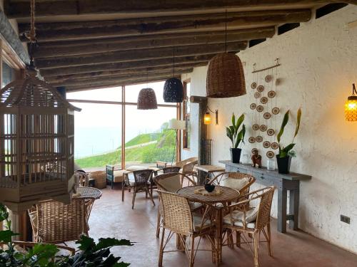 un comedor con mesas y sillas y una gran ventana en Posada Portal del Sol en Maitencillo