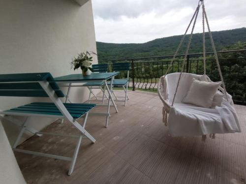 a porch with a swing and a table and a chair at "House of swallows" vacation home, close to Sofia in Makotsevo