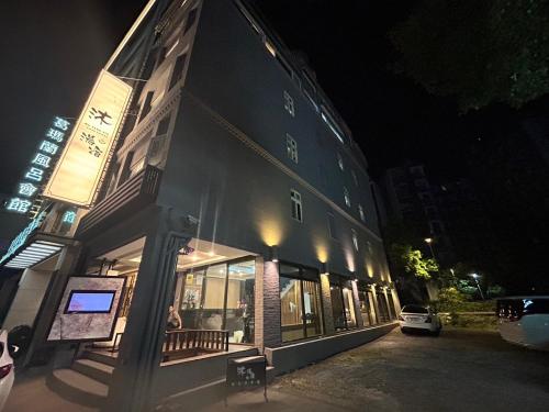 um edifício com uma placa ao lado à noite em 沐-湯宿溫泉行旅 em Jiaoxi