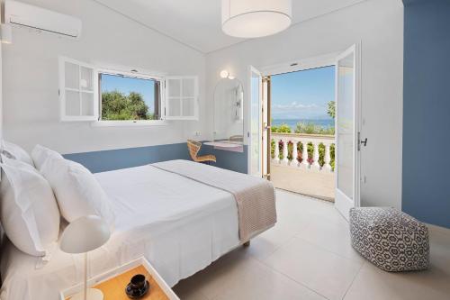 una camera da letto bianca con un letto e un balcone di Ionian Garden Villas - Villa Pietra a Benitses