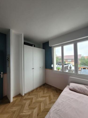 a bedroom with a bed and a large window at Logement de Ville 4 chambres proche de Lille in Tourcoing