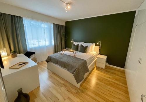 1 dormitorio con cama y pared verde en Hogland Apartments - 2 en Kotka
