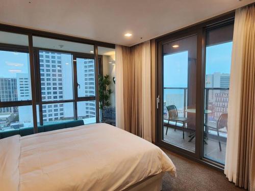 a bedroom with a large bed and large windows at ElbonThe Beach Haeundae in Busan