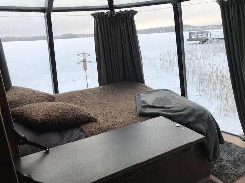 a bed in a room with a large window at Luxury Aurora glass Igloo, hot tub & sauna cottage in Rovaniemi