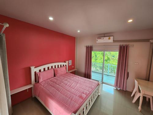 a bedroom with a red wall with a bed and a table at Vanilla Ville Resort in Khlong Thom