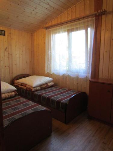 Habitación con 2 camas y ventana en una cabaña en OW ZŁOTA PLAŻA, en Mielno