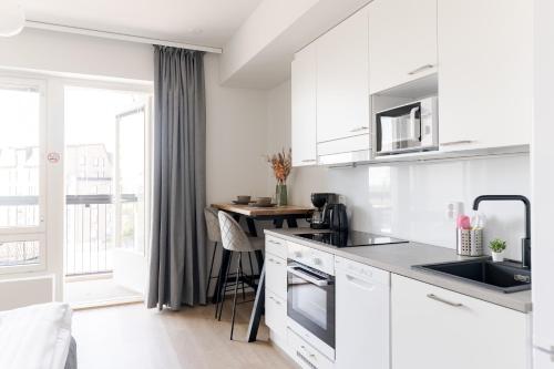 a kitchen with white cabinets and a table at Serviced Apartments Pirkkala by UHANDA in Tampere