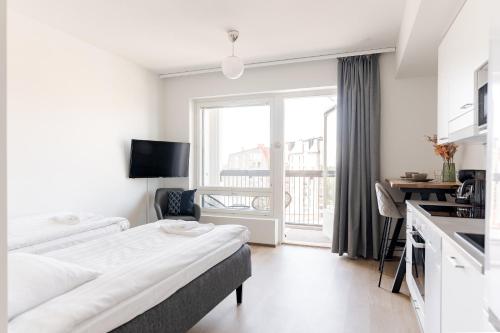 a room with two beds and a kitchen with a window at Serviced Apartments Pirkkala by UHANDA in Tampere