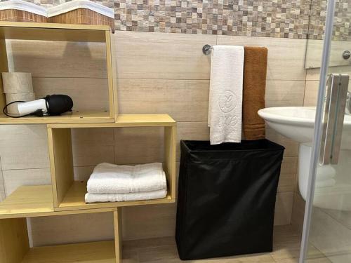 a bathroom with a sink and a shelf with towels at LaMarticata-LikesHome Garden in Triscina