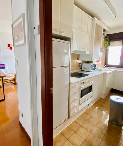 a kitchen with white cabinets and a white refrigerator at Vistas al Mar in Somo