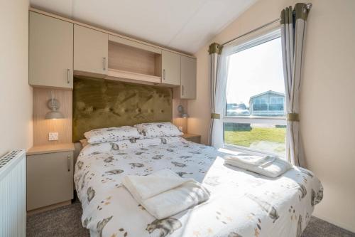 a bedroom with a bed and a large window at 3 Bed Static Caravan-Seton Sands in Longniddry