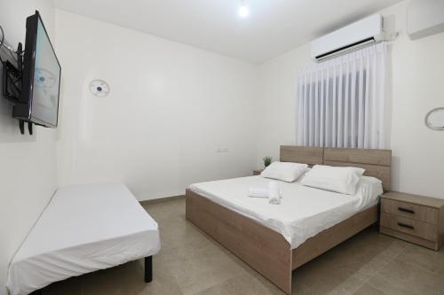 a bedroom with two beds and a flat screen tv at נופש הלל - וילה מהממת עם בריכה פרטית, וג'קוזי ליד הכנרת in Kallanit