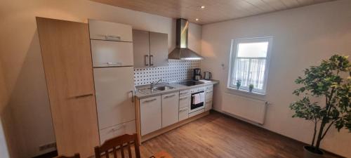 a kitchen with white cabinets and a sink and a window at Ferienwohnung "Gartenblick" Wolzhausen in Breidenbach