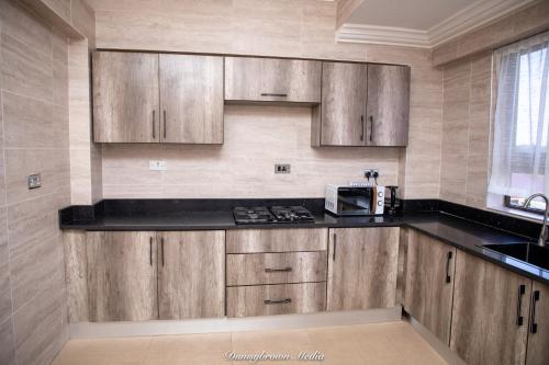 Una cocina con gabinetes de madera y microondas. en 2Bed Apartment Sleeps 4 - Parking Wifi, en Accra