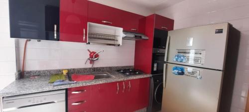 a kitchen with red cabinets and a white refrigerator at Appartement meublé Unica 2 Fes in Fez