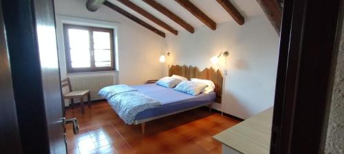 sypialnia z łóżkiem z niebieską pościelą i oknem w obiekcie La Rustica sul Lago di Tenno mansarda w mieście Tenno