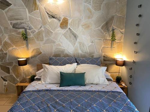 1 dormitorio con 1 cama con pared de piedra en Cocooning Tropic Studio avec Jacuzzi privatif, en Saint-Louis