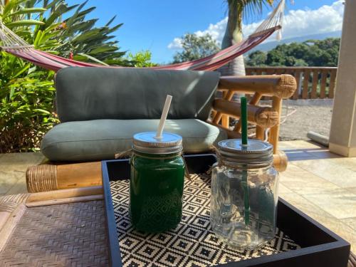 a table with two mason jars and a chair at Cocooning Tropic Studio avec Jacuzzi privatif in Saint-Louis