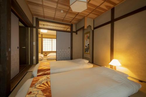 a bedroom with two beds and a lamp at Zenji 町家六堀 in Kyoto
