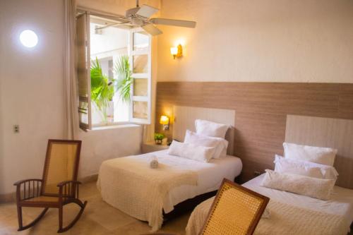 a hotel room with two beds and two chairs at Hotel Boutique Don Pepe in Santa Marta