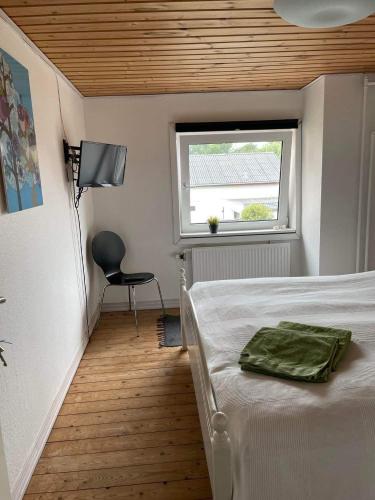 a bedroom with a bed and a window and a chair at Fru Hald in Løkken
