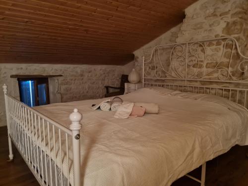 - une chambre avec un lit blanc et un mur en pierre dans l'établissement L'Hégoa, à Montpellier-de-Médillan