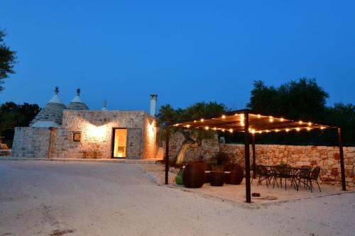 a patio with an umbrella and tables and chairs at Trulli di Titti - Luxury Country House in Castellana Grotte