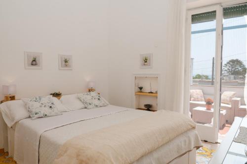 a white bedroom with a bed and a large window at Casa Rubina in Capri