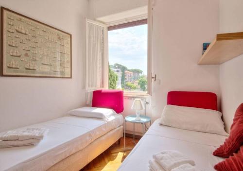 Cette chambre dispose de 2 lits avec des chaises rouges et d'une fenêtre. dans l'établissement Dolce Acqua Flexyrent apartment Terrace & Parking - NO AC, à Rapallo