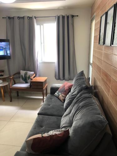 uma sala de estar com um sofá com almofadas em A Passos da Areia Apartamento 2 Quartos no Coração da Badalada Praia do Morro - WiFi Fibra e Netflix para sua Estadia em Guarapari