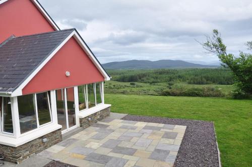 a red and white house with a view of a field at Grace's Landing in Sneem